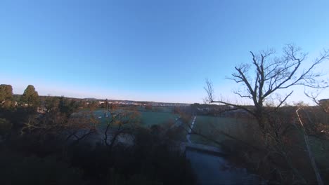 vuelo a baja altura sobre un pantano, seguido de aterrizaje en un campo de rugby al amanecer