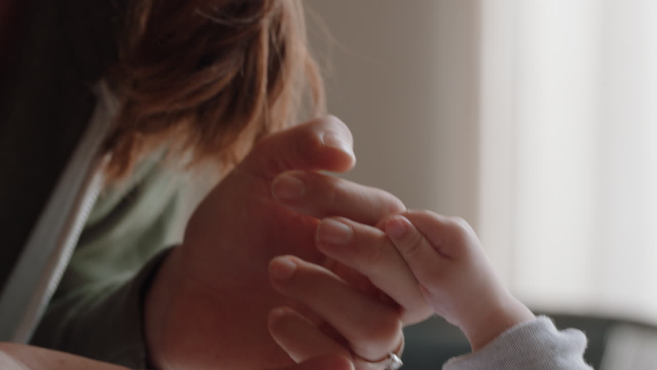 mother holding baby hand touching fingers nurturing newborn caring for infant at home enjoying motherhood