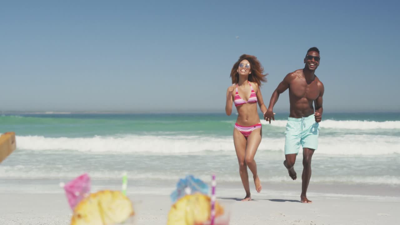 African American couple running side by side at beach