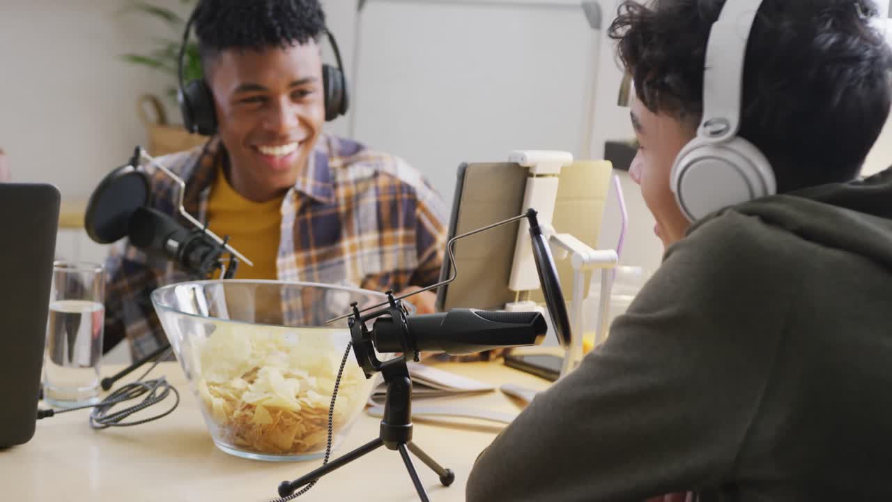 Happy diverse male teenage friends using laptop and recording podcast, slow motion