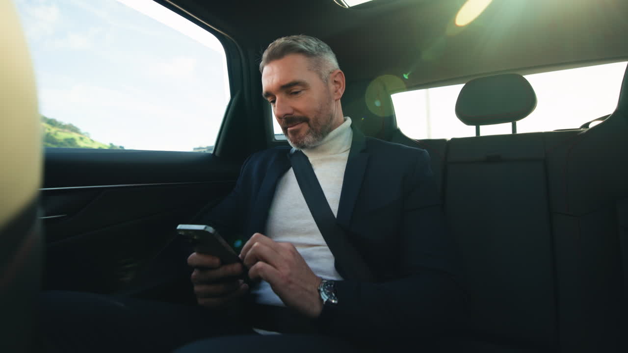 Man in Suit Using Smartphone in Car
