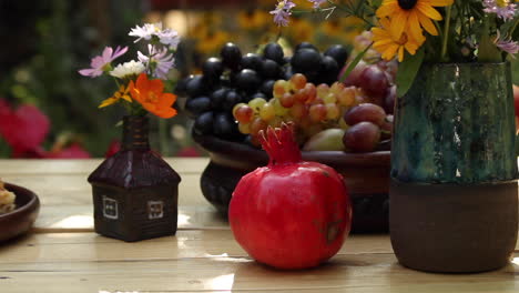 garden table with bowl of fresh grapes, red pomegranate and baklava in garden