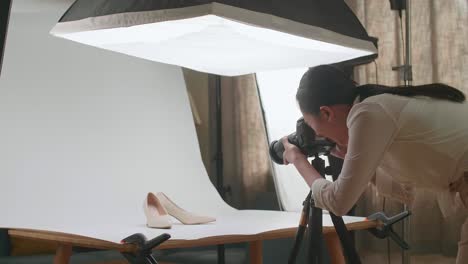 fotógrafa asiática entrando en el estudio doméstico y tomando fotos de los zapatos de las mujeres