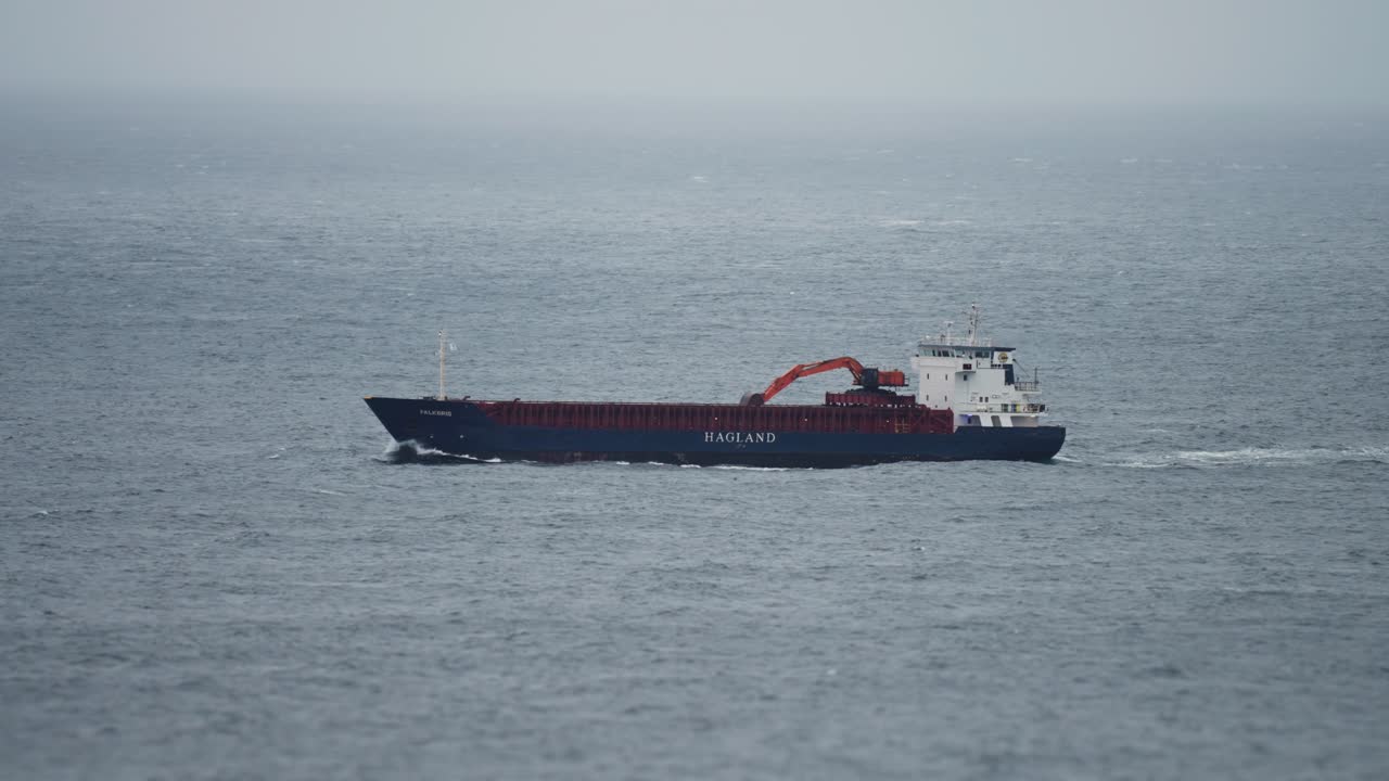 A barge in the sea in rough weather. Slow-motion, pan follow.