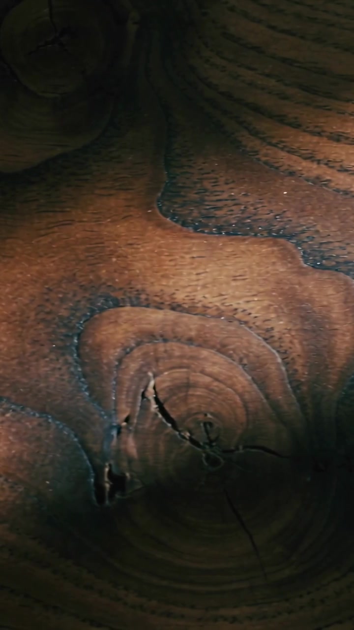 Vertical video: Panning camera revealing wood at home showing knots rings varnish to reveal texture