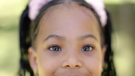 retrato de una feliz chica afroamericana sonriendo en el jardín