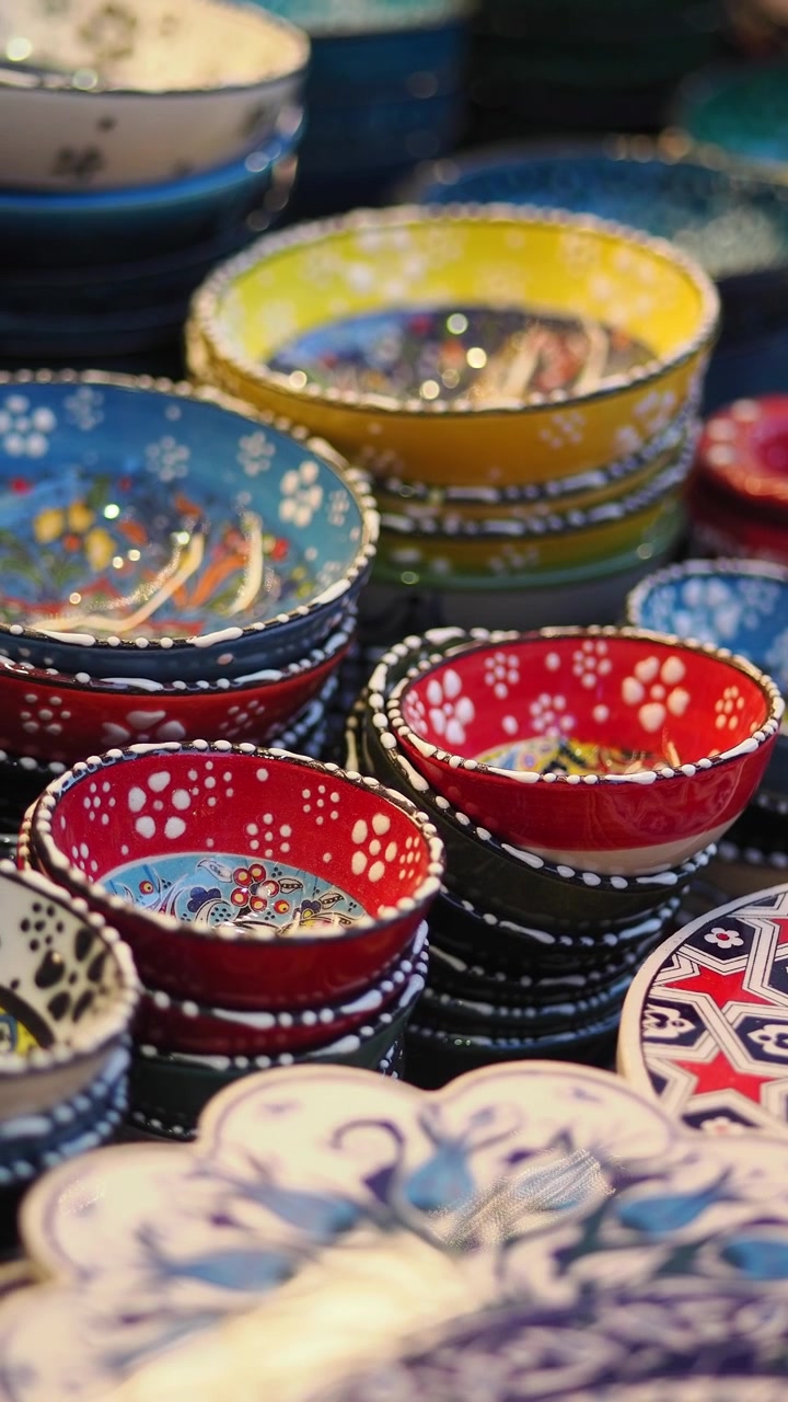 Ciotole in ceramica colorate e dipinte a mano esposte in un mercato.