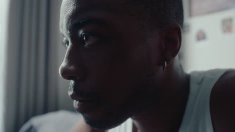 young pensive black man sitting in the bedroom