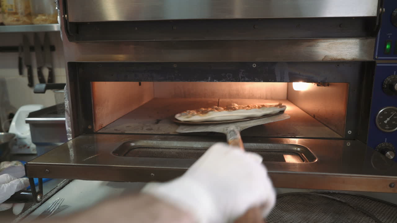 Pizza baking in oven. ?hef takes pizza from oven in traditional restaurant