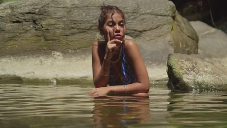 on the tropical island of trinidad, a young girl in a bikini enjoys the waterfall and river