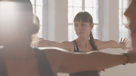 joven mujer caucásica embarazada en clase de yoga practicando pose guerrera disfrutando de un estilo de vida saludable en grupo haciendo ejercicio en el gimnasio al amanecer.