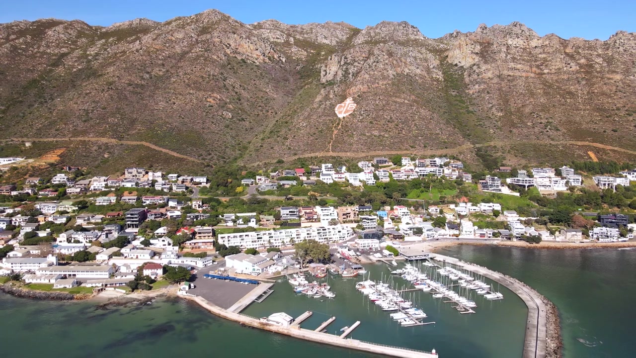 Puerto de Gordon's Bay y marina de yates bajo la ladera de la montaña en False Bay. Dron.