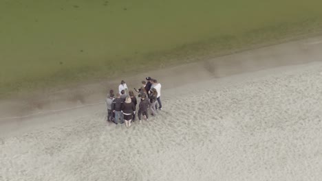 group of people taking photos on a beach by a lake