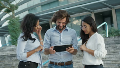 tall handsome project manager explaining project idea to his two colleagues with tablet computer