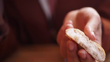 close up of someone breaking a piece of white bread with their hands