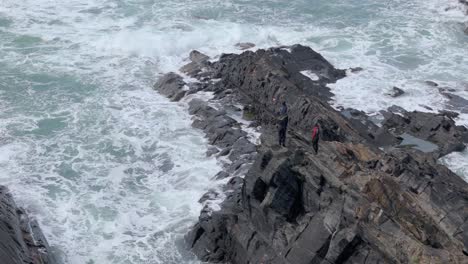 men standing fishing on rocky coastline of pembrokeshire blue lagoon waterfront in wales