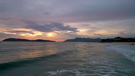 Surfers-waiting-to-catch-a-wave-during-sunset-at-Pentai-Tengah-Beach,-Malaysia