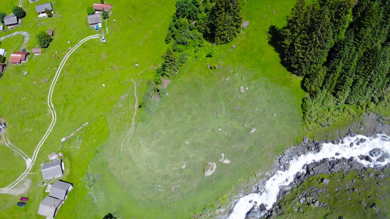 Bird&rsquo;s eye view above peaceful mountain village by roaring stream, Switzerland