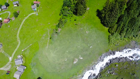bird’s eye view above peaceful mountain village by roaring stream, switzerland