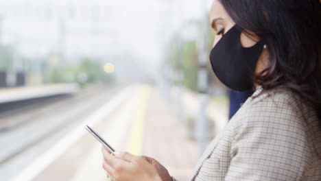 Viajeros-De-Negocios-En-La-Plataforma-Ferroviaria-Con-Teléfonos-Móviles-Usando-Máscaras-Faciales-De-Ppe-Durante-La-Pandemia