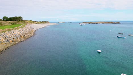 Flight-along-coastline-at-Bordeaux-Guernsey-with-crystal-clear-sea-and-boats-at-anchor-on-bright-calm-day