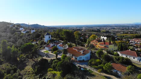 Drone-shot-of-some-houses-and-windmills-on-the-ridge-in-Palmela,-Portugal