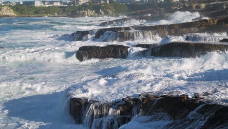 tumultuous ocean waves crashing into rocks, shooting water straight up into the sky