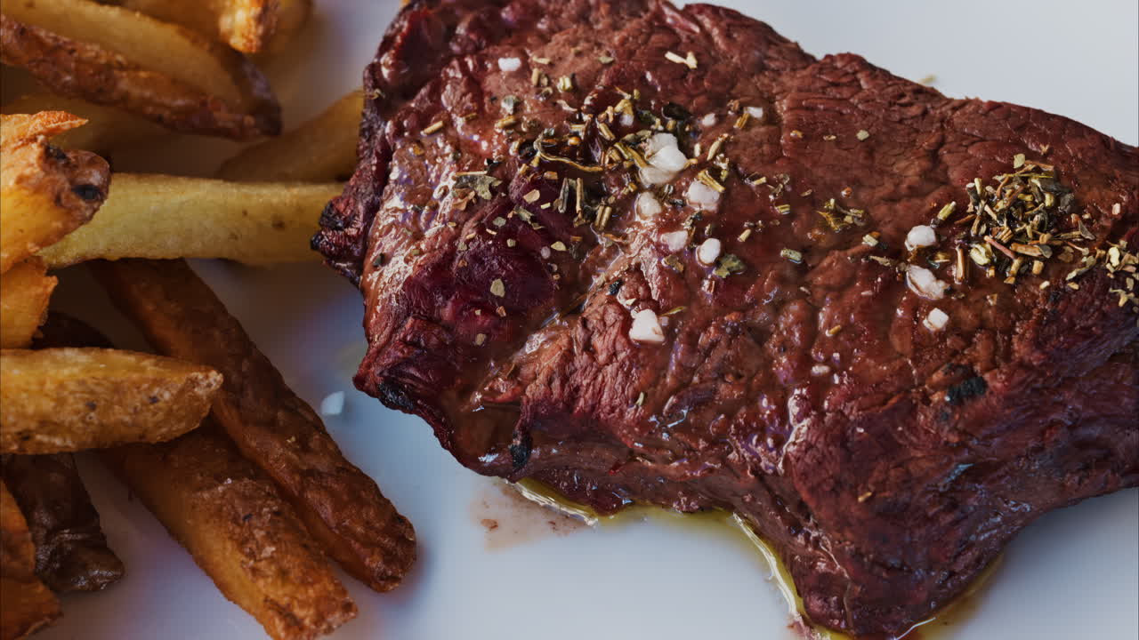Close up of stake with fries and salad on a white plate at a restaurant
