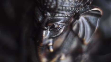 close up shot of ganesha figurine with incense stick burning on background