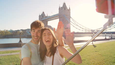 a cheerful young couple waving during a selfie