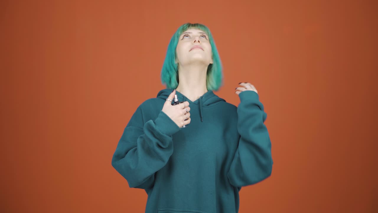 향수를 뿌려 좋은 향기가 나는 젊은 여성.
