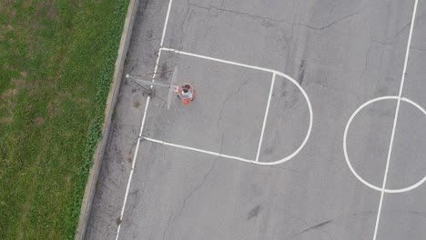 ein mann spielt basketball auf einem leeren basketballfeld und lässt seinen basketball erfolgreich in den basketballring fallen