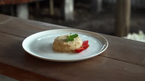un pequeño pastel de napoleón con fresas en la parte superior de pie en un plato blanco