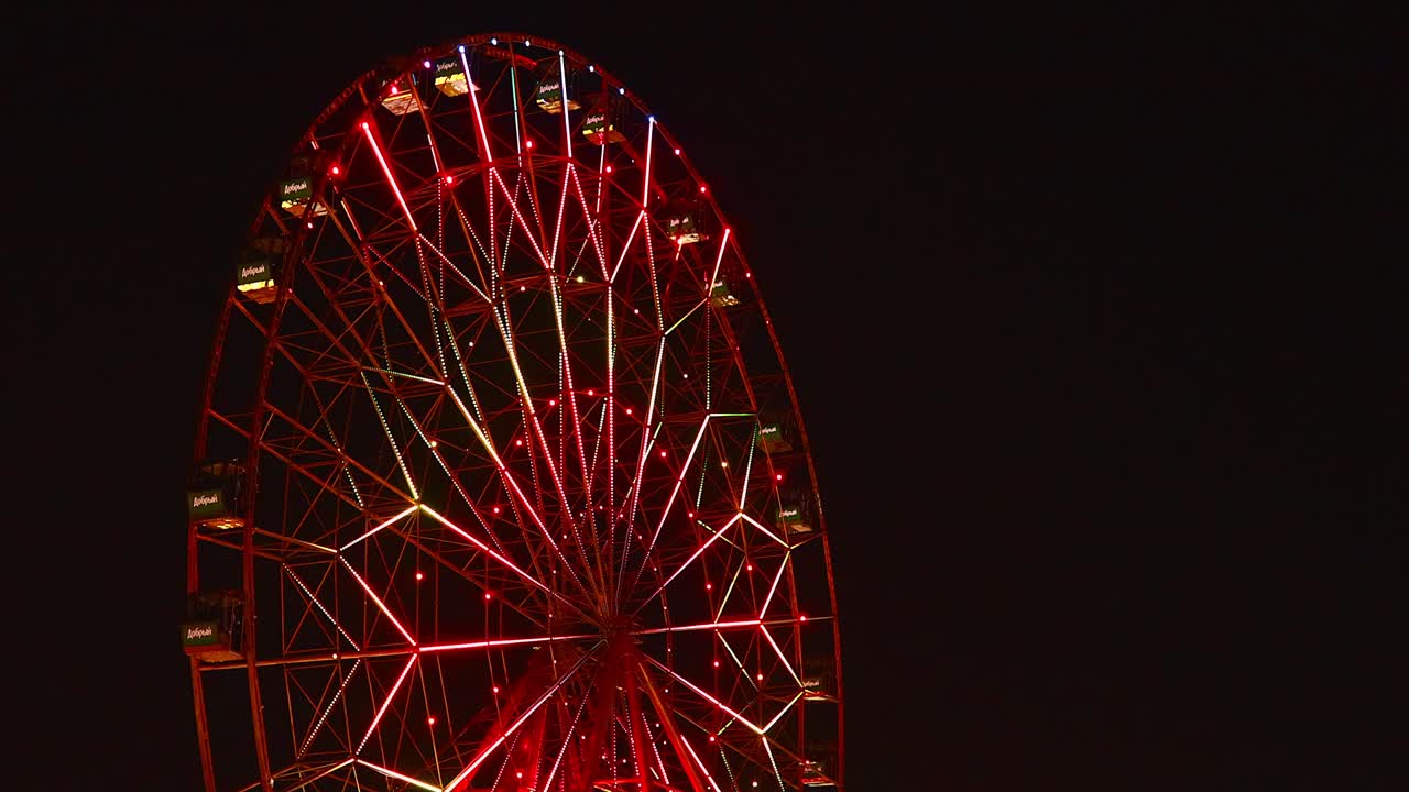 blurred unfocused video of brightly lit ferris wheel ride spinning at night