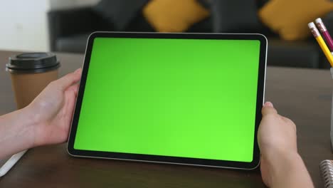 mujer sosteniendo una tableta digital con pantalla verde y dispositivo táctil navegando por internet.