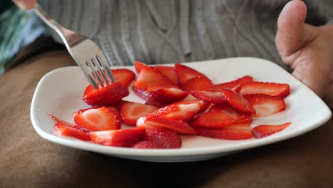 person eating sliced strawberries