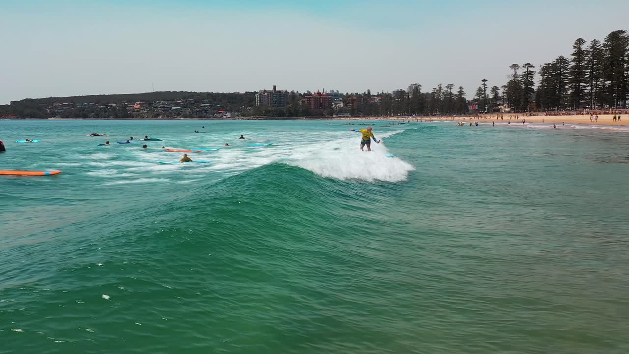 Aerial of people learning to surf on small ocean waves. Surf School on Manly Beach, Sydney, Australia.
