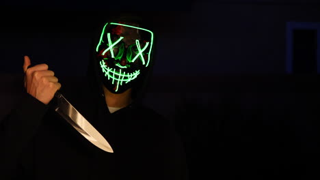 a creepy slasher killer in a generic anonymous halloween horror mask pulling a knife on his murder victim