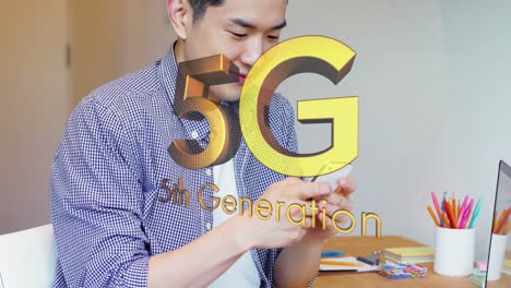 animation of gold 5g text over smiling asian man using smartphone at desk
