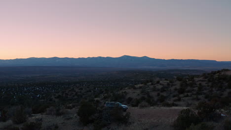 Orbiting-scenic-aerial-of-SUV-camping-on-remote-overlook-with-campfire,-4K