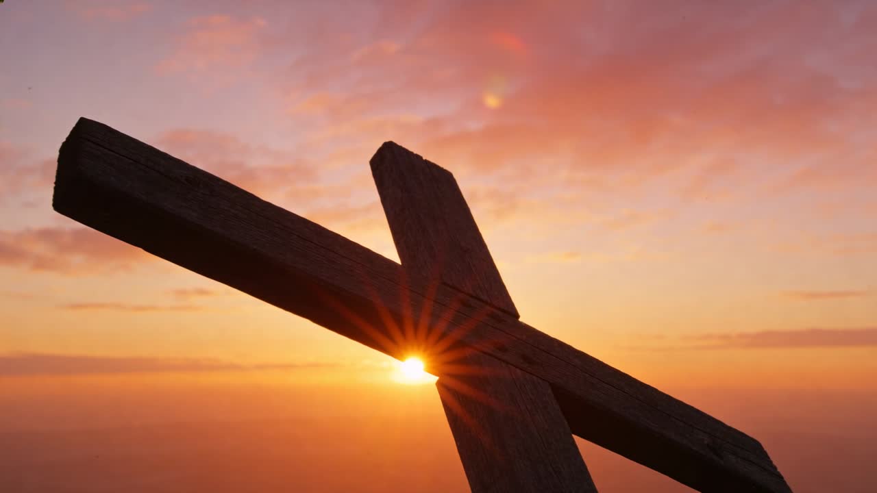 Croce di legno inquadrata che si inclina all'alba, luce solare che si sposta dal giunto verso la trave inferiore e le nuvole.