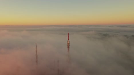 Foggy-start-to-a-cold-morning-in-Menorca,-Spain-with-cell-tower-sticking-out-above-the-clouds