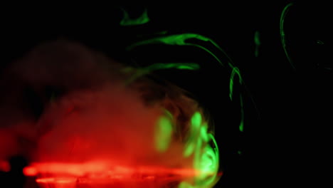 Slow-tendrils-of-smoke-pass-through-red-and-green-lasers-on-black-background,-abstract-overlay