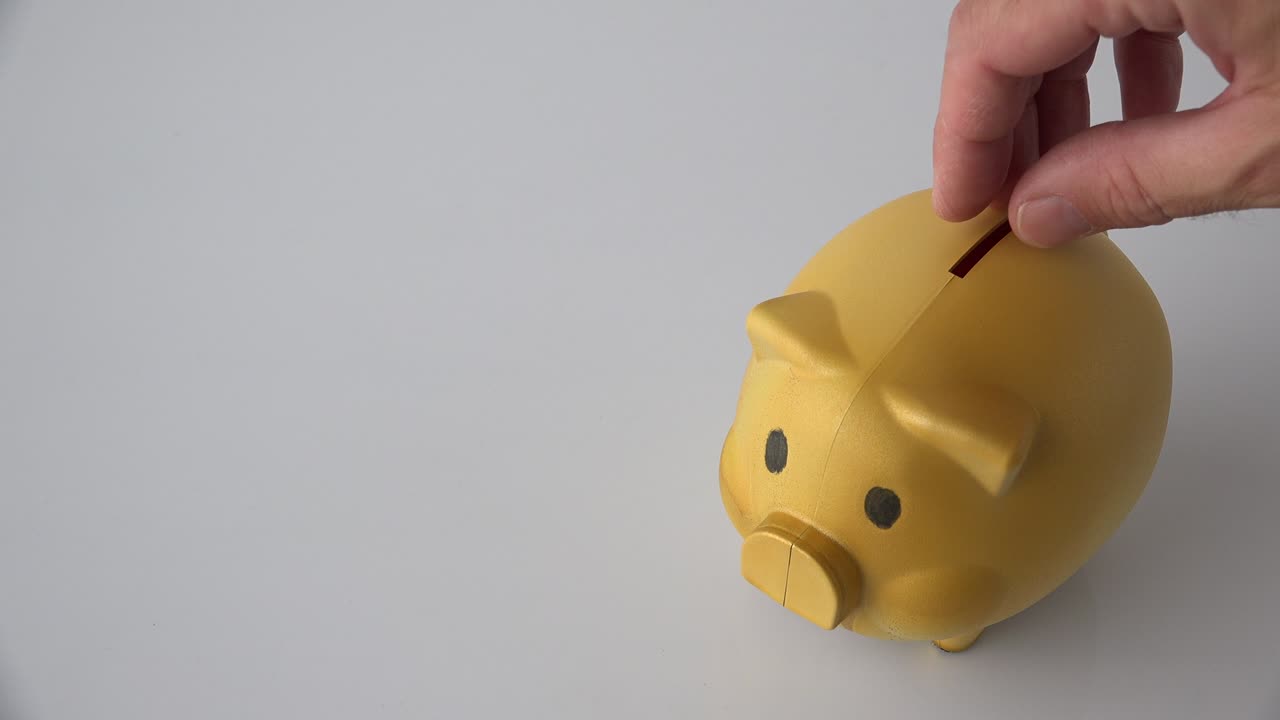 Mano che inserisce monete in un salvadanaio