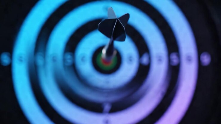 Precision in Action: A Hand Aims a Dart at a Vibrant Bullseye Target, Capturing the Essence of Focus and Targeting Skills