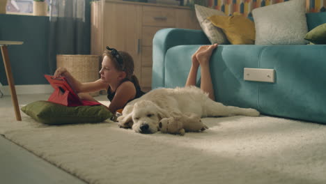 girl and dog relaxing at home with tablet