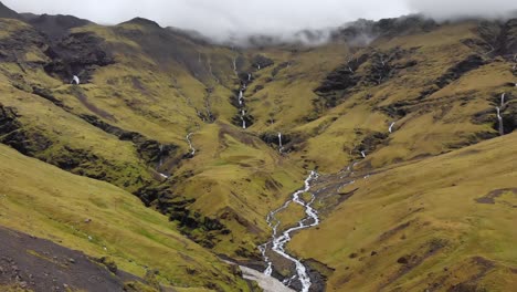 aerial of foggy mountains with small streams of water in iceland