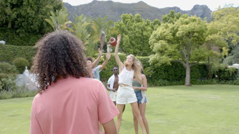 young biracial woman throws a football in a garden