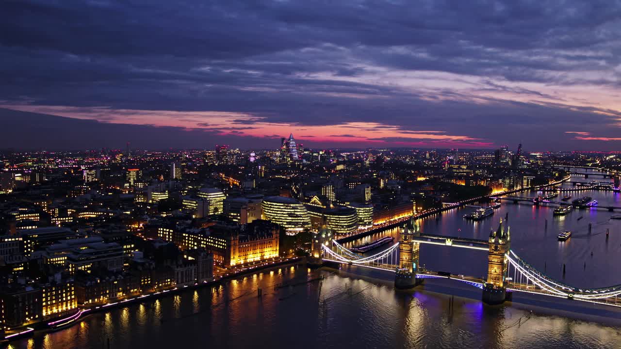 Aerial view of a cityscape at dusk, showcasing illuminated bridges and buildings