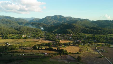 golden rice fields mountain village in the valley surrounded by green forest and mountains, mueang khong in the evening, drone of small village in the mountains